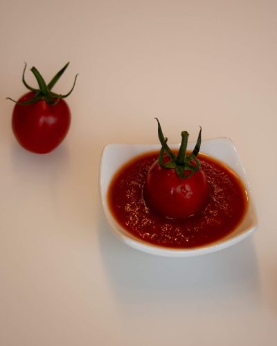 Cherry rajčica uronjena u umak od rajčice na bijeloj podlozi