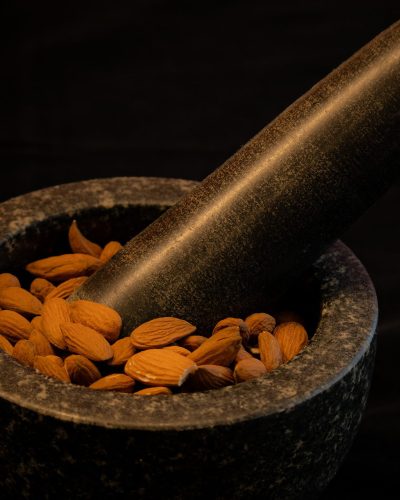 Bademi u kamenom mužaru s tučkom, fotografija prirodnih sastojaka u tamnom ambijentu