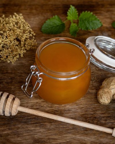 Staklenka meda s biljem i drvenom žlicom za med, fotografija