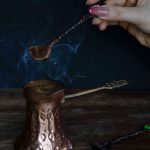 Ruka koja miješa kavu u bakrenoj džezvi